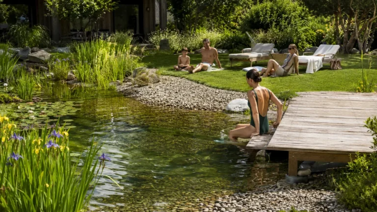 Staw kąpielowy w ogrodzie ze strefą plażową i leżakową nad brzegiem