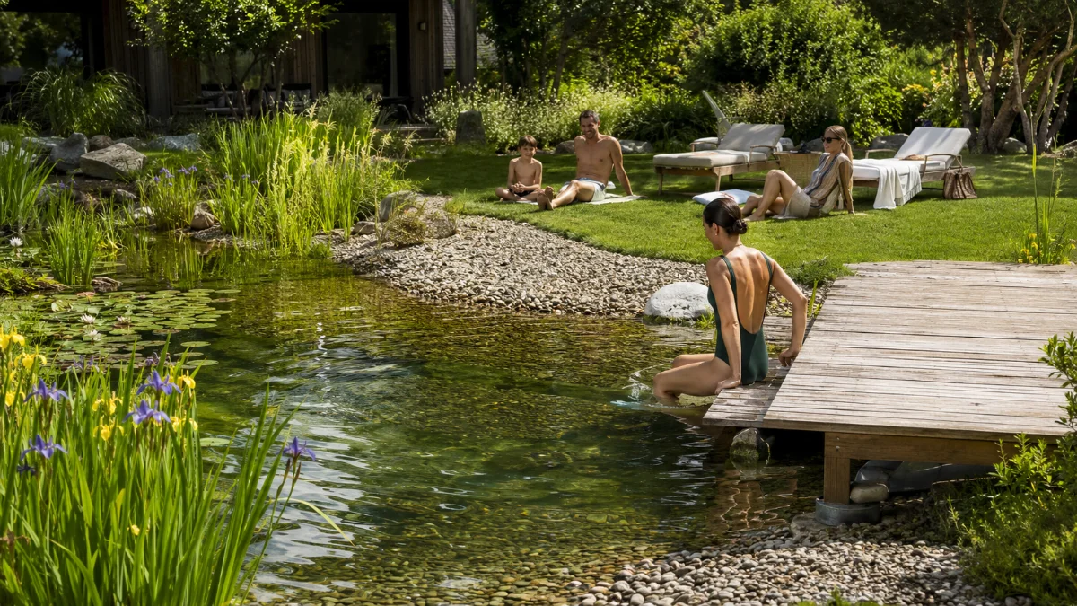 Staw kąpielowy w ogrodzie ze strefą plażową i leżakową nad brzegiem